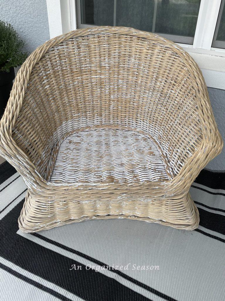 A rattan chair with bits of white chippy paint on it. 