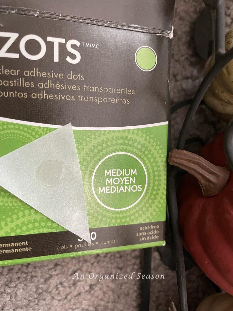 A clear adhesive glue dot used to secure each pumpkin inside the obelisks.