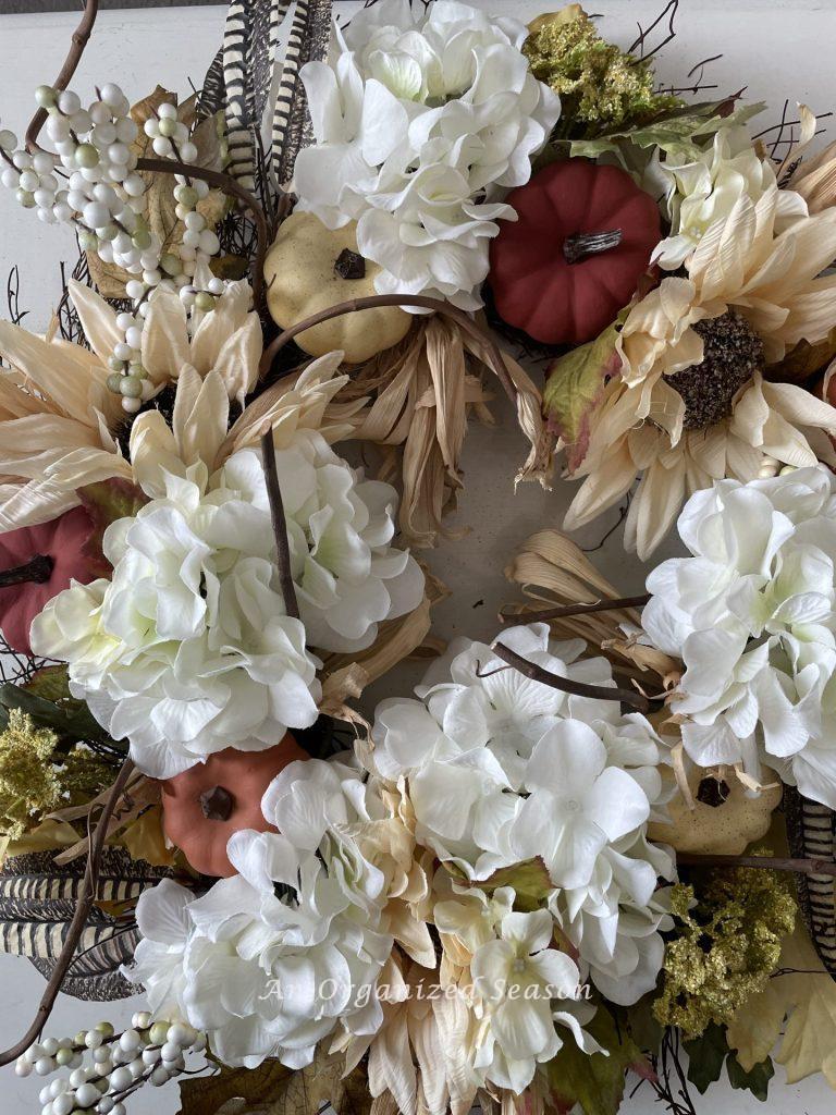 A fall wreath with terra cotta and burgundy pumpkins. It was updated for a Budget decorating ideas for fall porch.