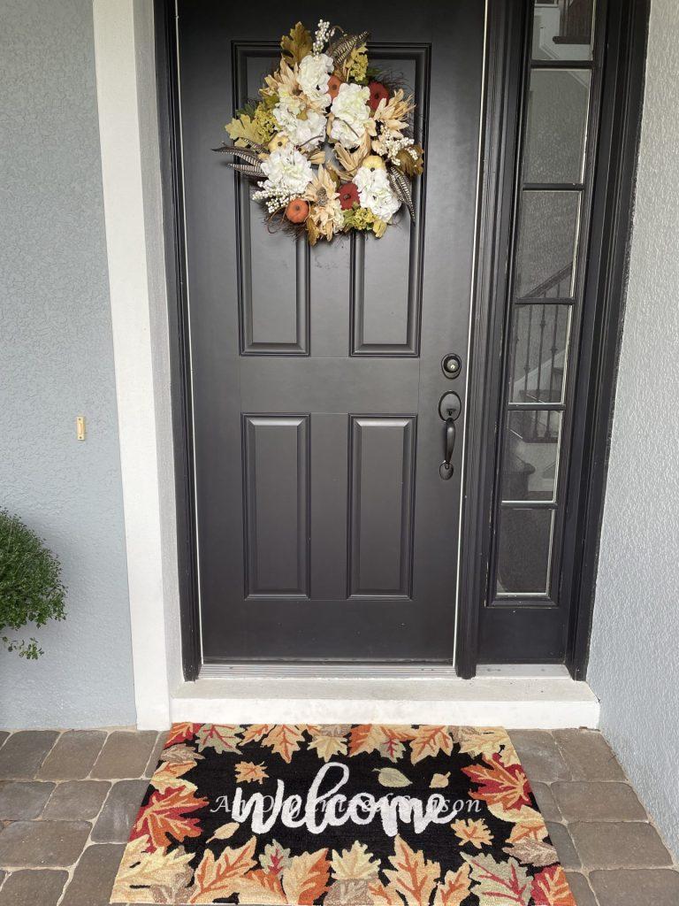 Front door with a matching Fall wreath and welcome mat.