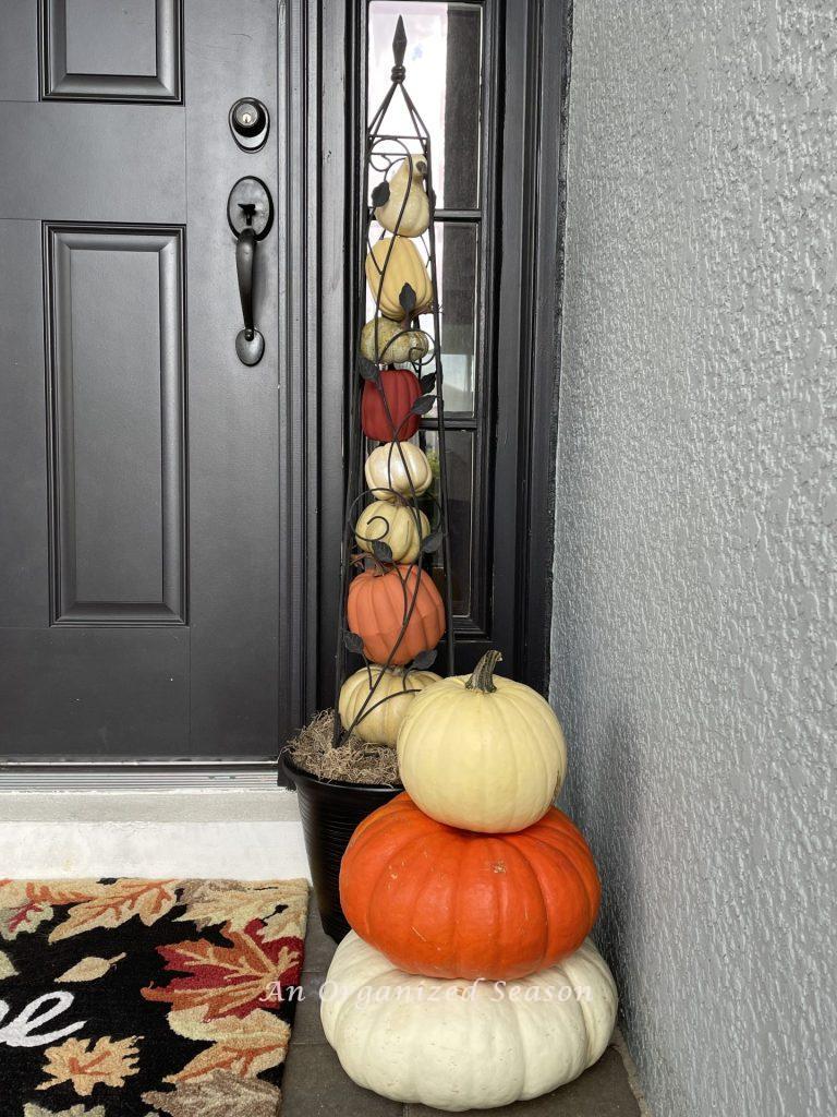 A pumpkin obelisk behind three stacked pumpkins. 