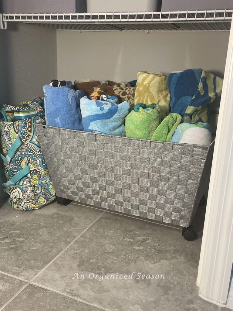 Beach towels stored in a basket with wheels in the bathroom closet. 
