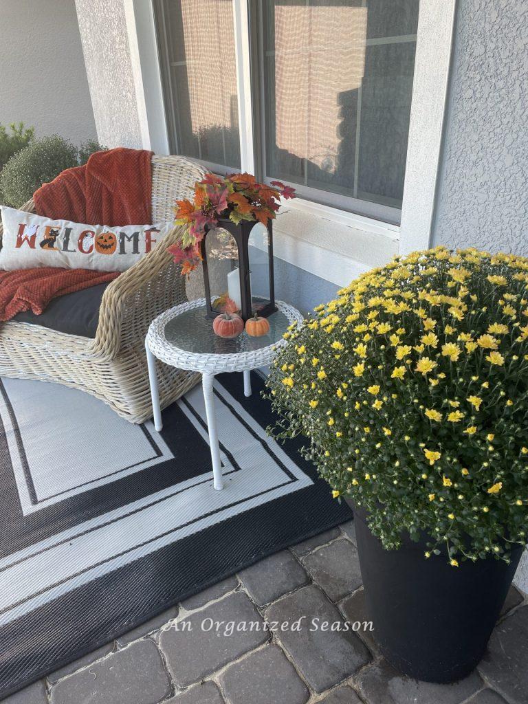 A large potted yellow mum sitting on a porch. Buy it from Costco for a Budget decorating ideas for fall porch.