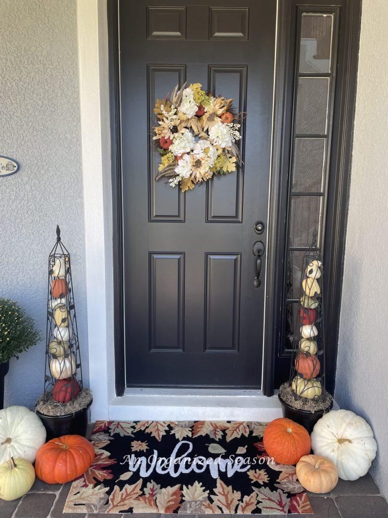 Two pumpkin obelisks decorate a front porch for fall.