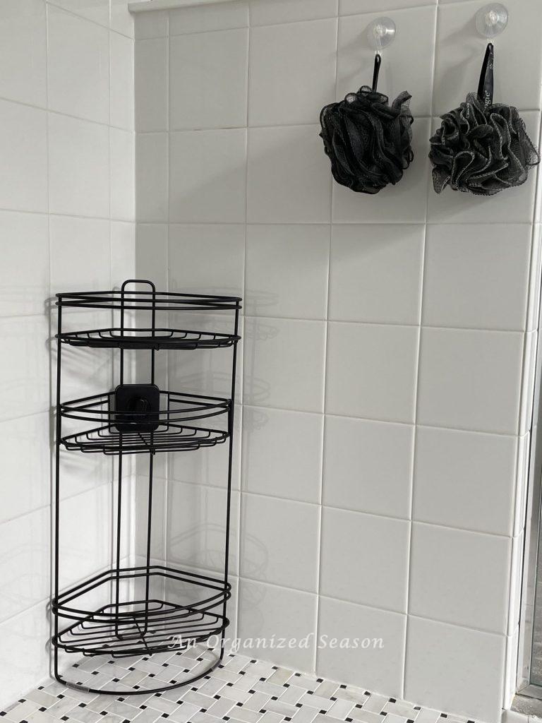 Black metal shower shelf in a walk in shower.