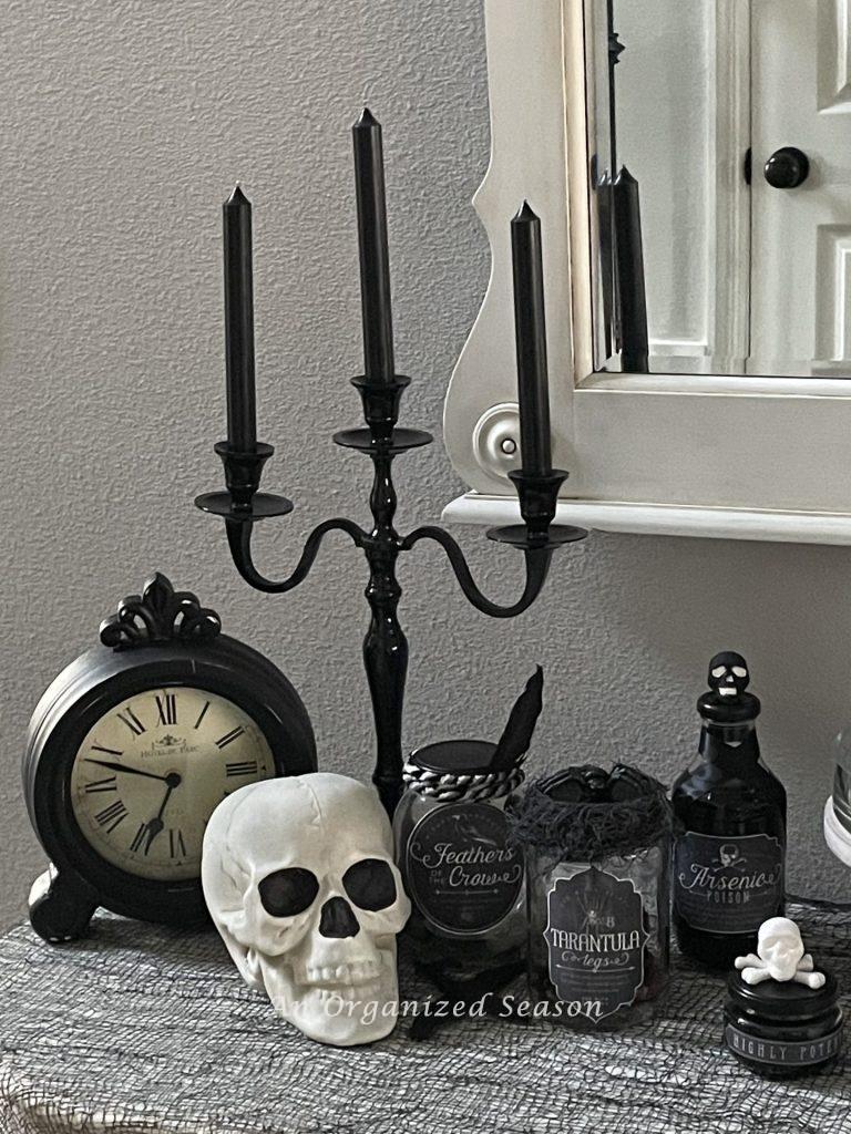 A black candelabra, antique clock, skull, and potion bottles. 