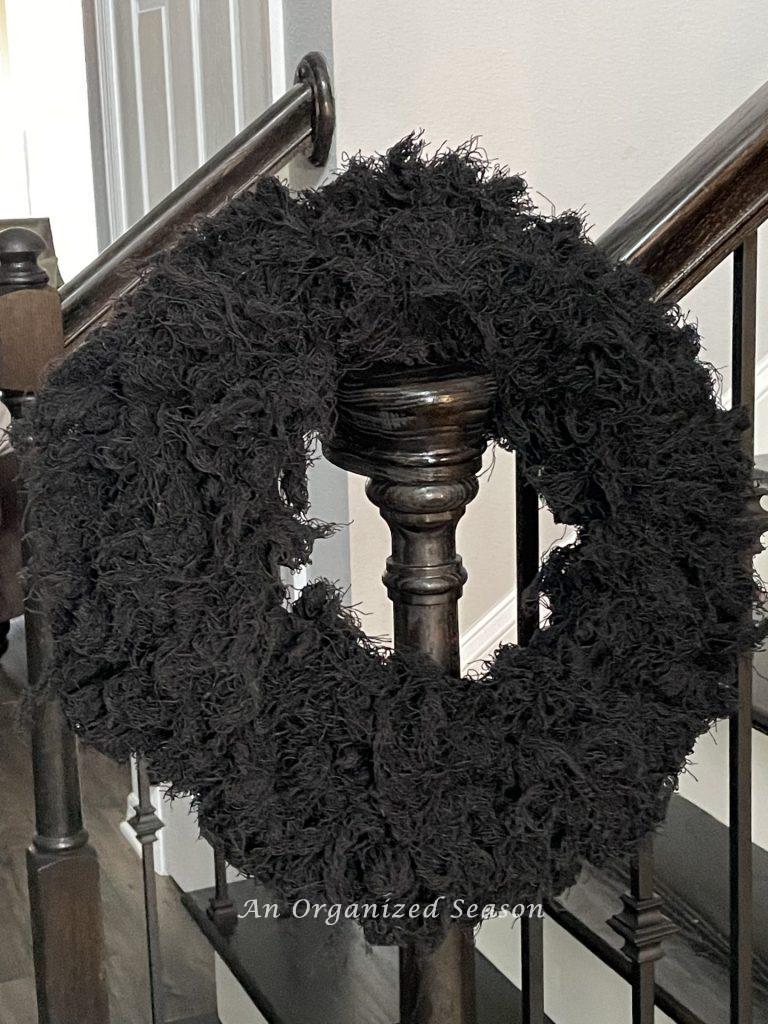 A black wreath made from Dollar Tree creepy cloths. 