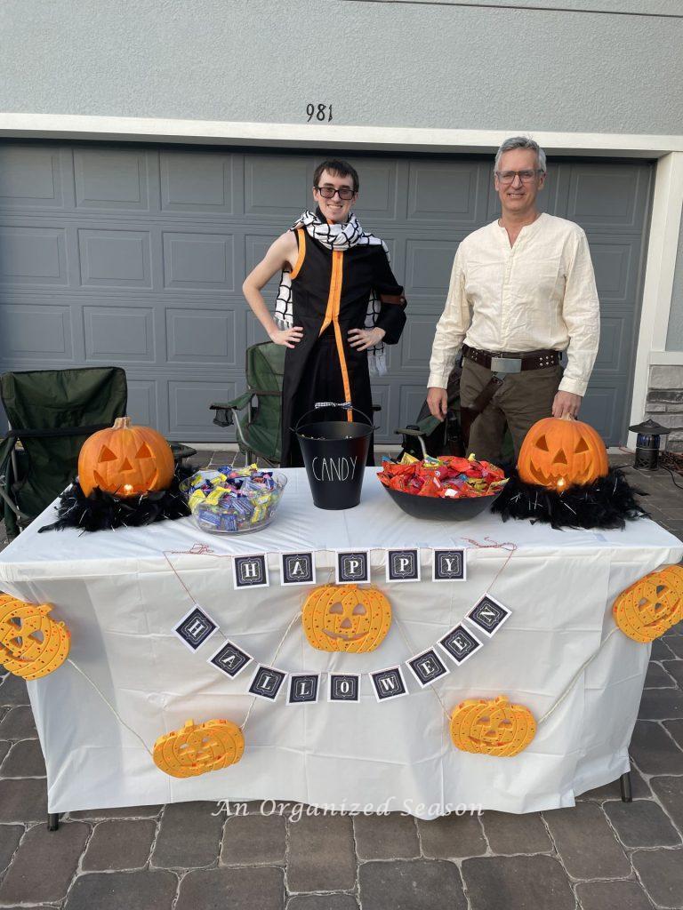 Two people dressed up and handing out candy for Halloween.
