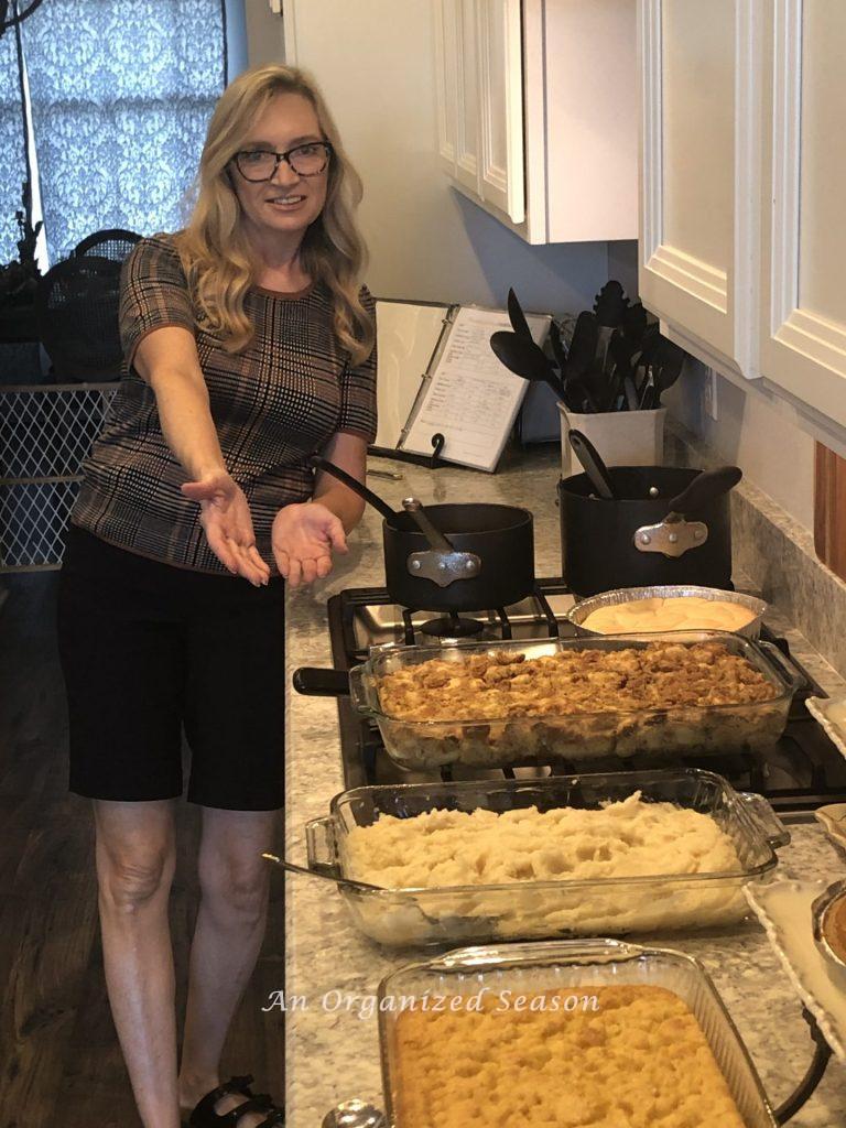 A woman showing a Thanksgiving food spread.