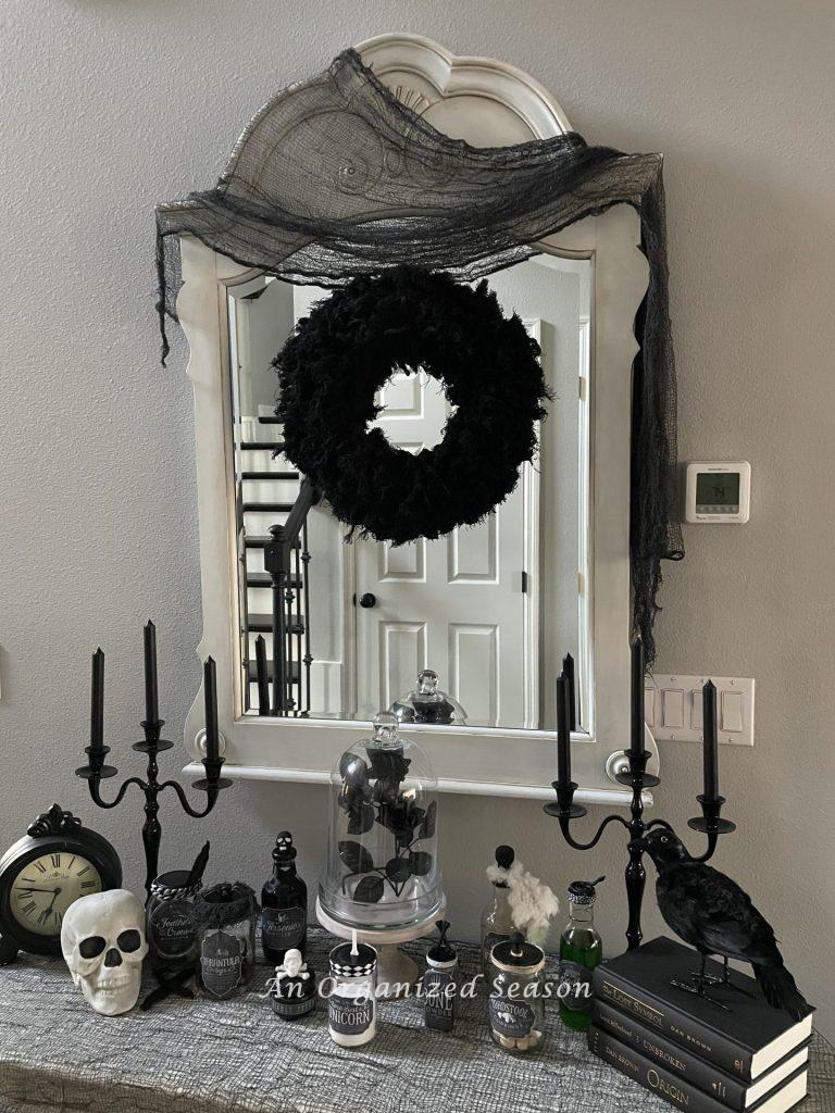 An entryway table and mirror decorated for Halloween. 