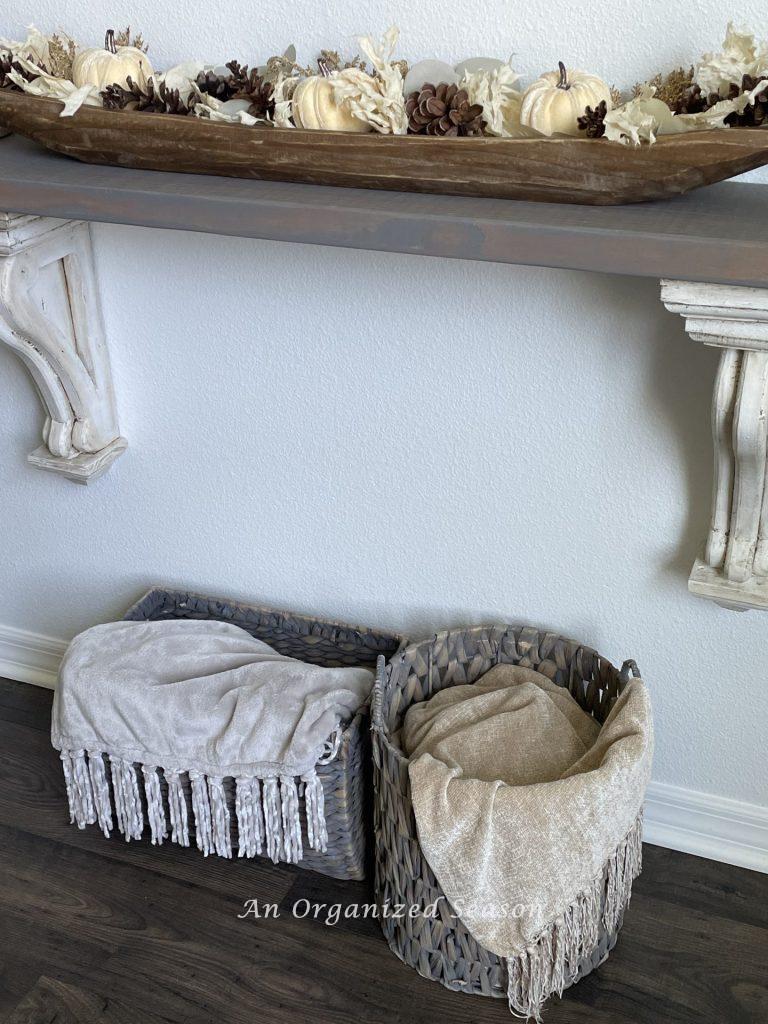 Fall home tour showcasing two baskets holding cozy throw blankets in front of newly painted white walls. 