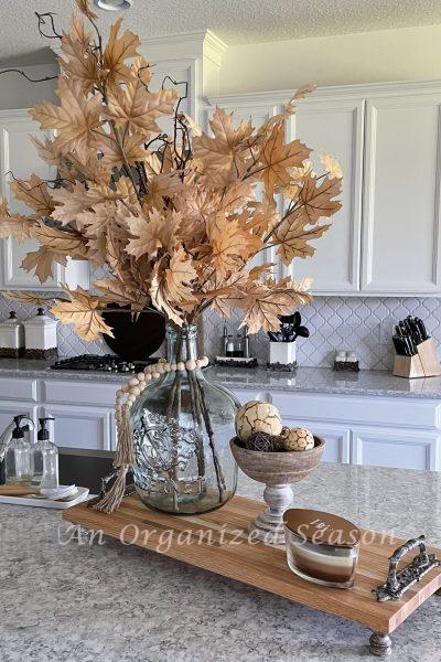 Maple leaves in a glass vase on a kitchen counter