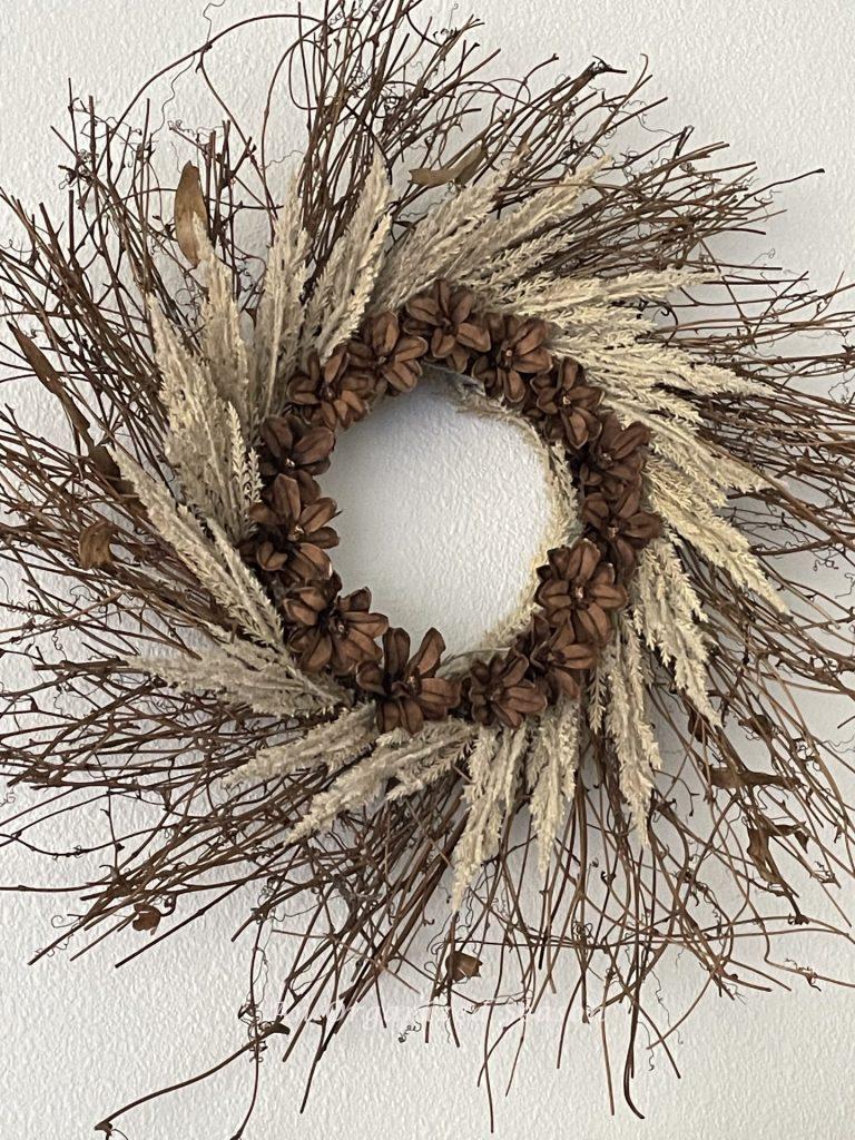 Fall Home tour showcasing a pinecone flower wreath hanging on a white painted wall. 