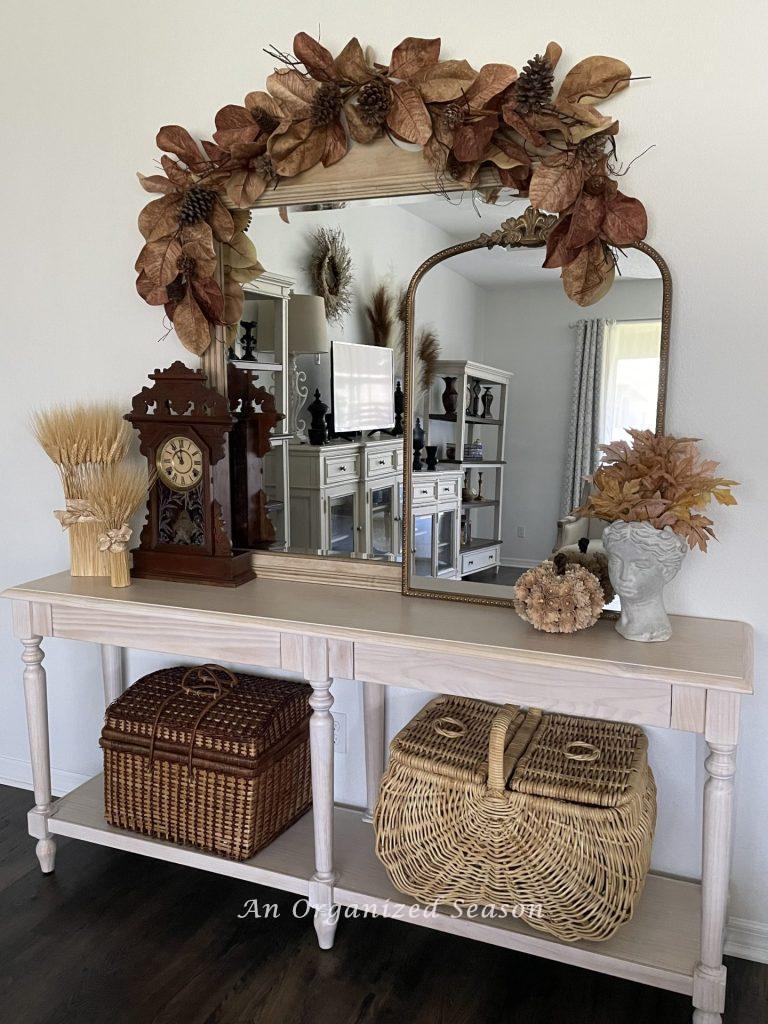 A console table and two mirrors decorated for a Fall home tour in a front of a wall painted the color white.