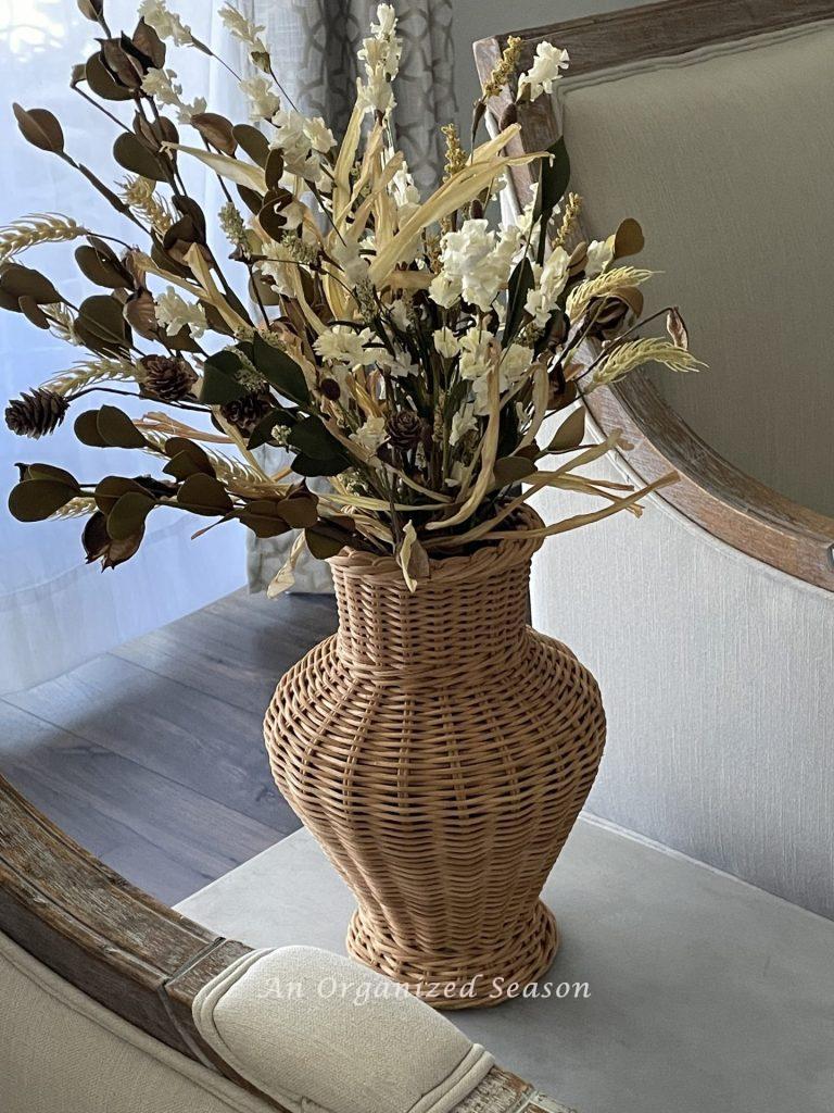 A basket shaped like a vase that's filled with fall florals. 