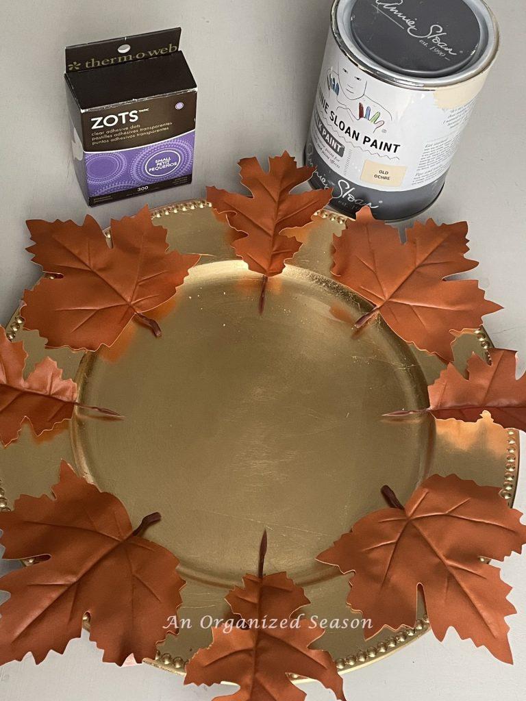 Gold charger, faux leather leaves, paint, and glue dots used to make super easy DIY plate chargers.