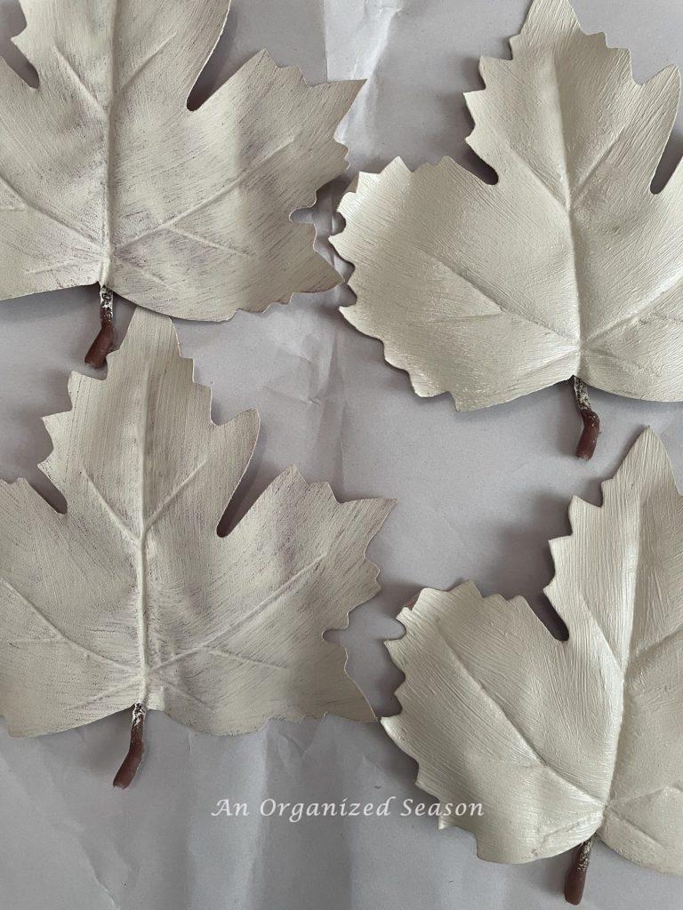 Four leather leaves painted white and used to make super easy DIY plate chargers.