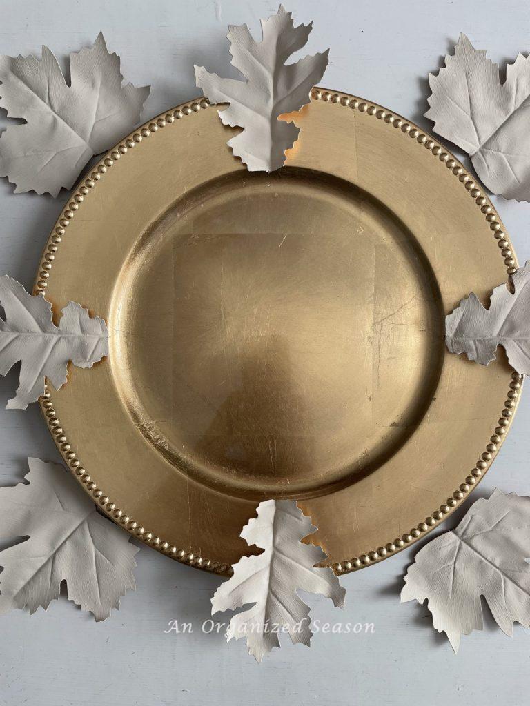 A gold charger with white leaves used to make super easy DIY plate chargers.