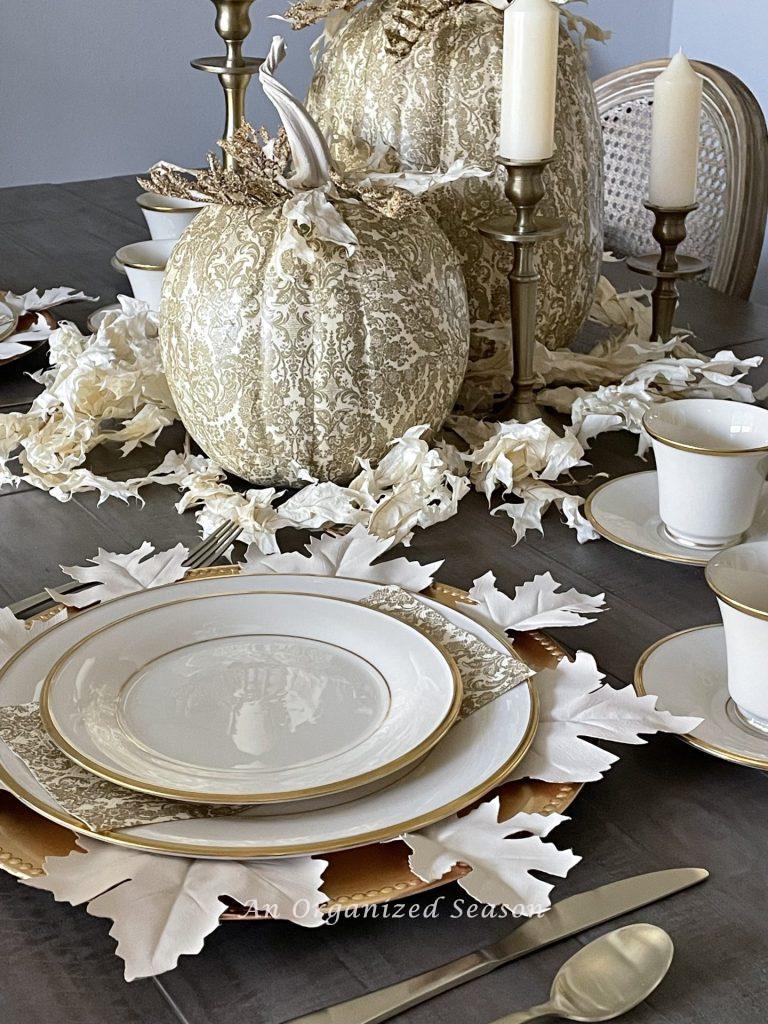 Dining room tables with cream and gold decoupaged pumpkins and table setting to match. 