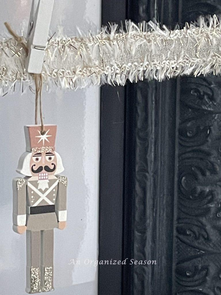 A nutcracker Christmas ornament hanging from a ribbon. 