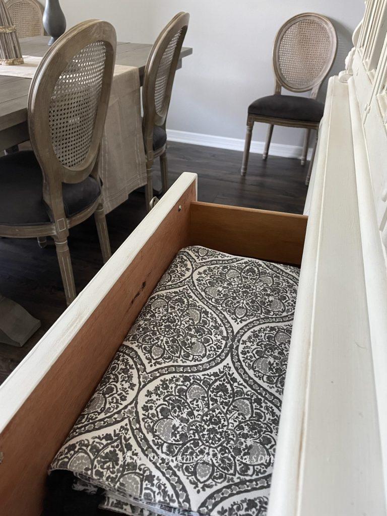 Store table runners in a china cabinet drawer to declutter the dining room.