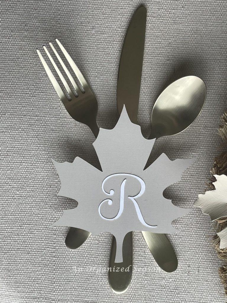 Eating utensils with a leaf place card that holds the initial "R."