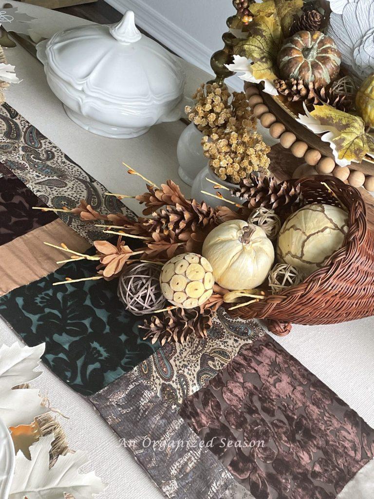 A scarf being used as a table runner,  great ideas for a thrifted Thanksgiving table.