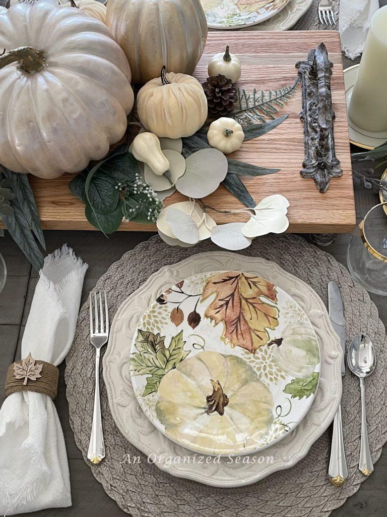 A table set with pumpkin dishes and a centerpiece with pumpkins. 