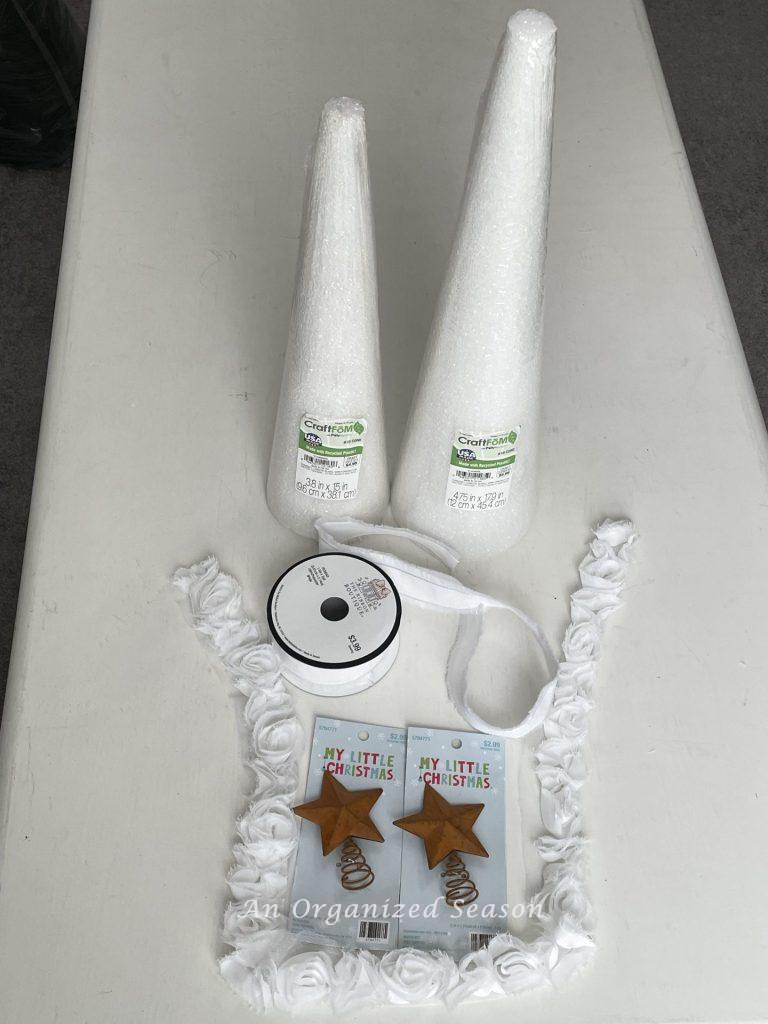 Styrofoam cone, ribbon, white rose trim and star tree topper that will be used to make a DIY cone Christmas tree.