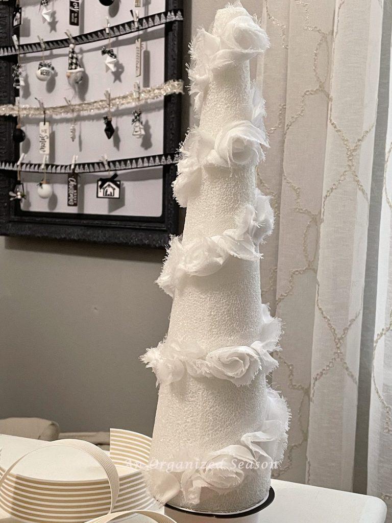 A styrofoam cone with white rose trim wrapped around it used to make a DIY cone Christmas tree. 