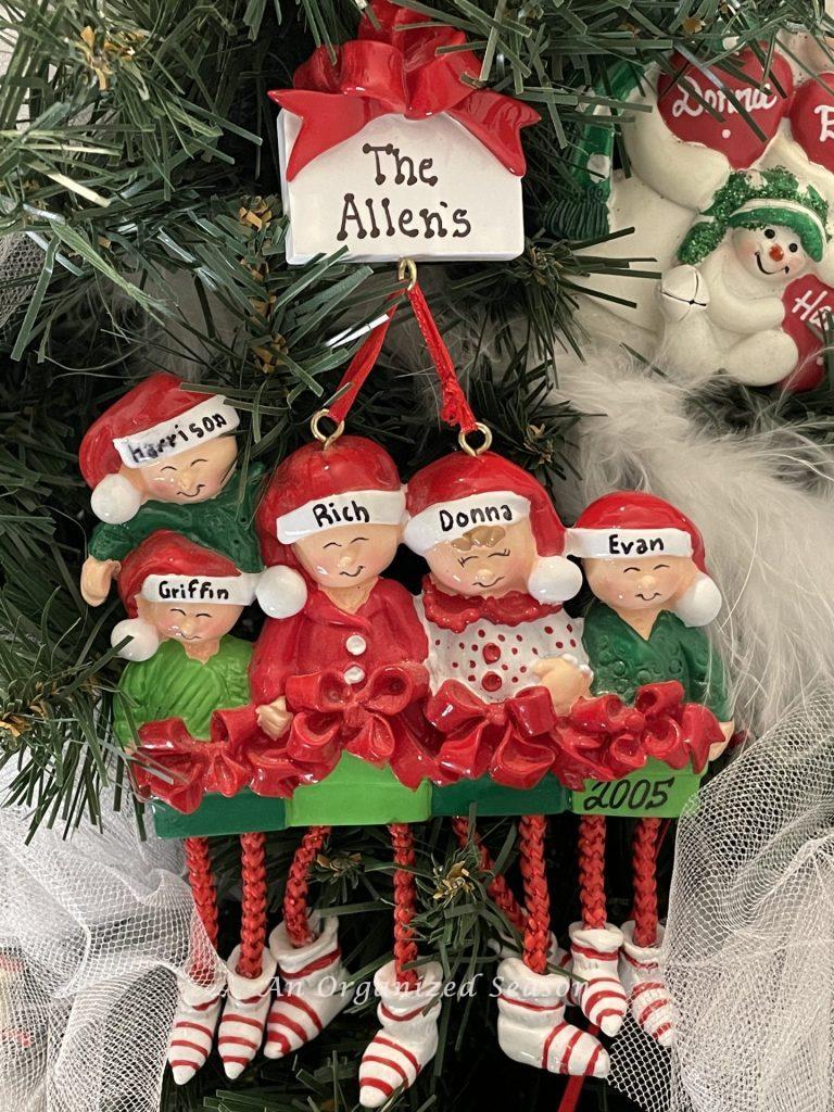 A personalized Christmas ornament showing a family of five with Santa hats on, showing our family keepsake ornament tradition.
