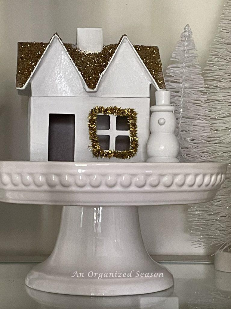 A Christmas village house sitting on a cake plate.