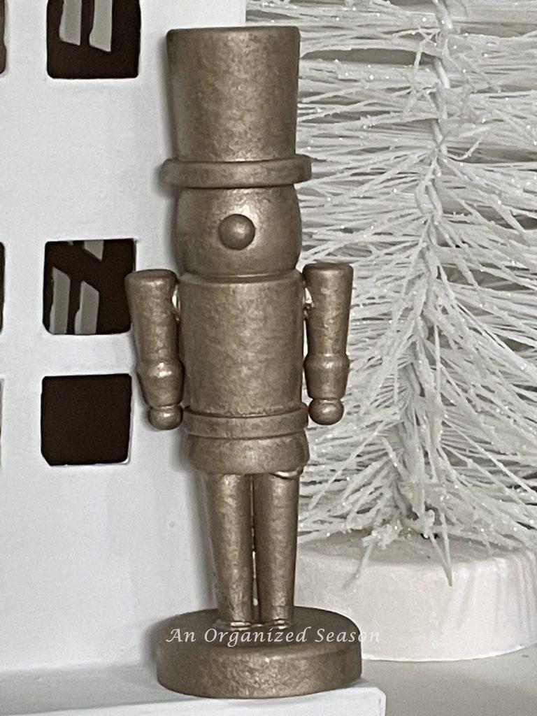 A miniature wood nutcracker that was spray painted gold.