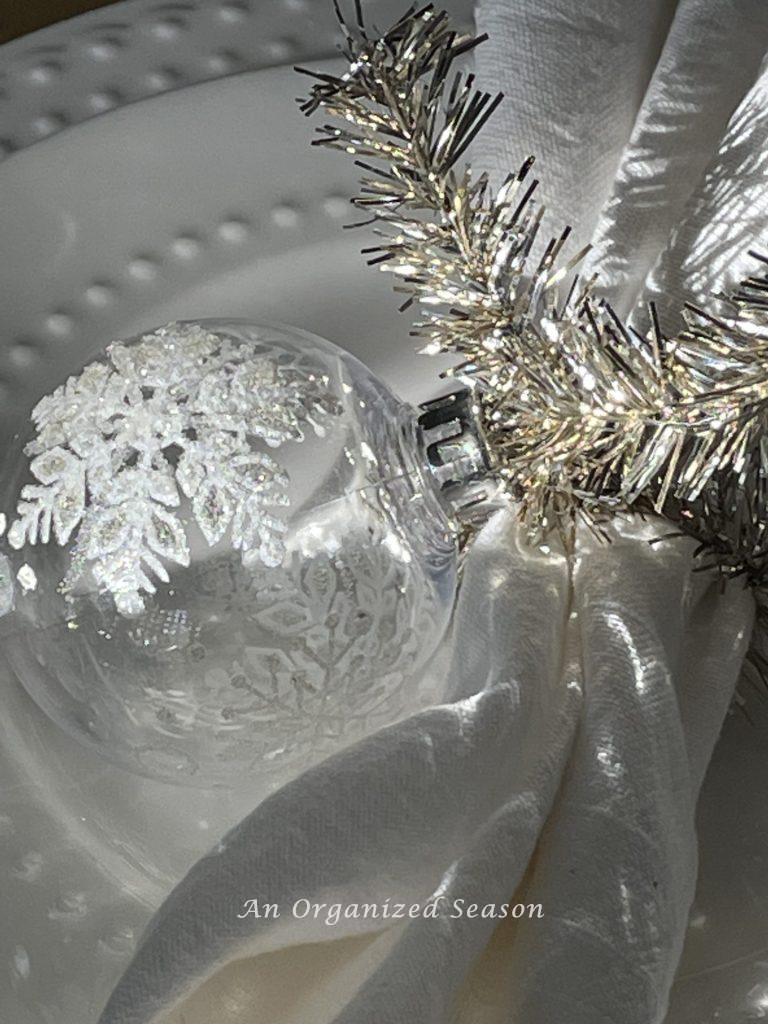 A dining room napkin ring made from a clear Christmas ornament with a snowflake on it. 