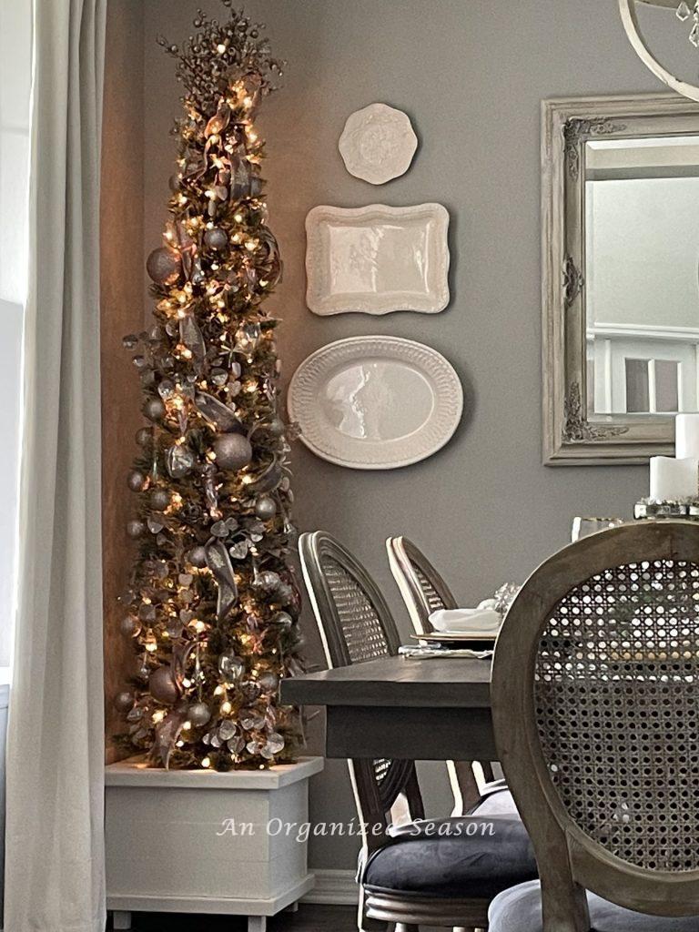 A lit and decorated Christmas tree in a dining room. 