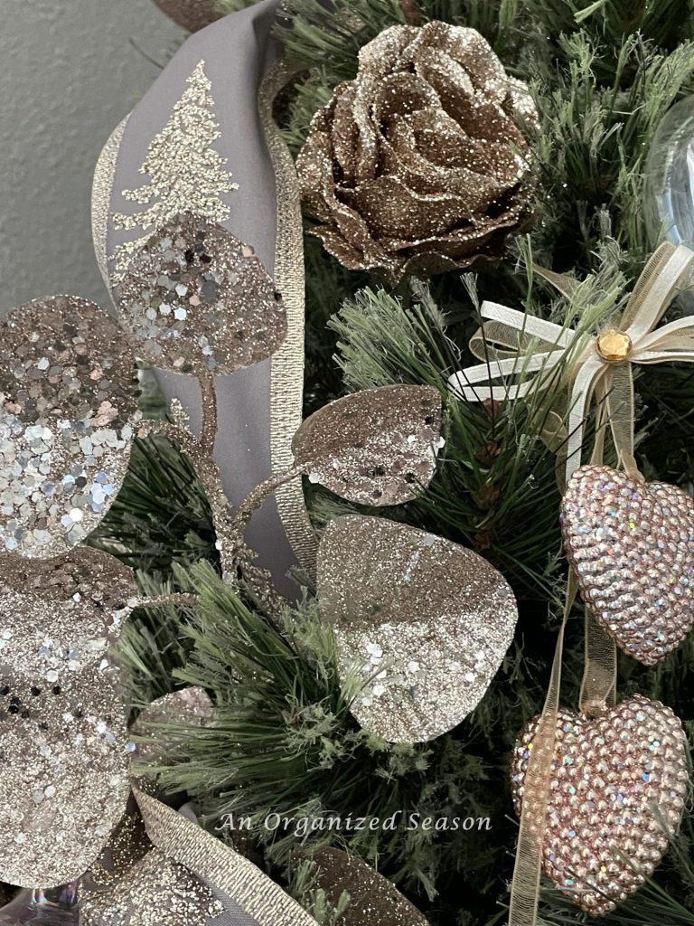 A glitter pink rosebud and garland on a dining room Christmas tree. 