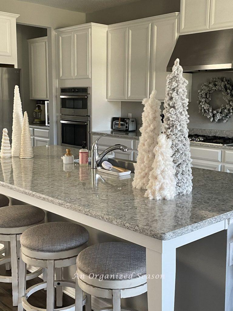 A kitchen island holding six yarn cone Christmas trees will help get you organized for holiday entertaining.