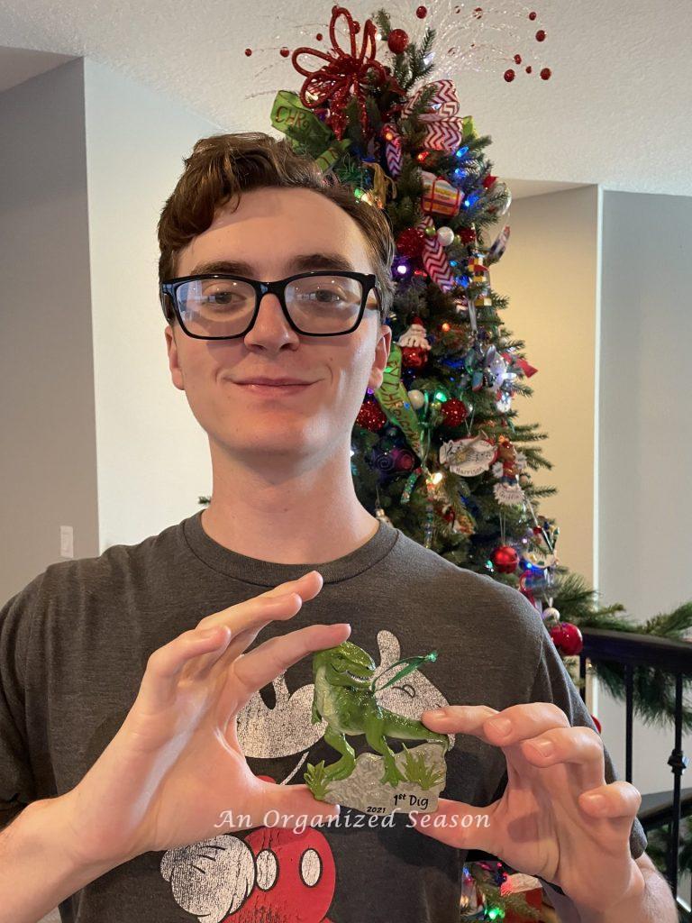 A young man holding a dinosaur ornament.