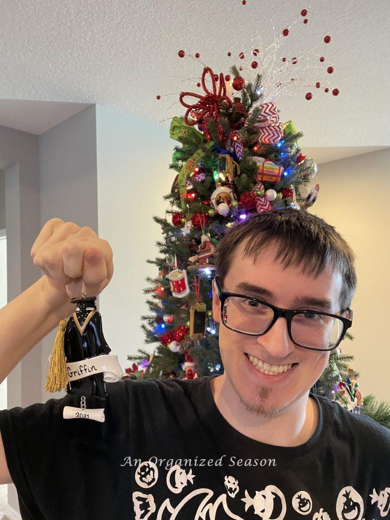 A young man holding a graduation Christmas ornament.