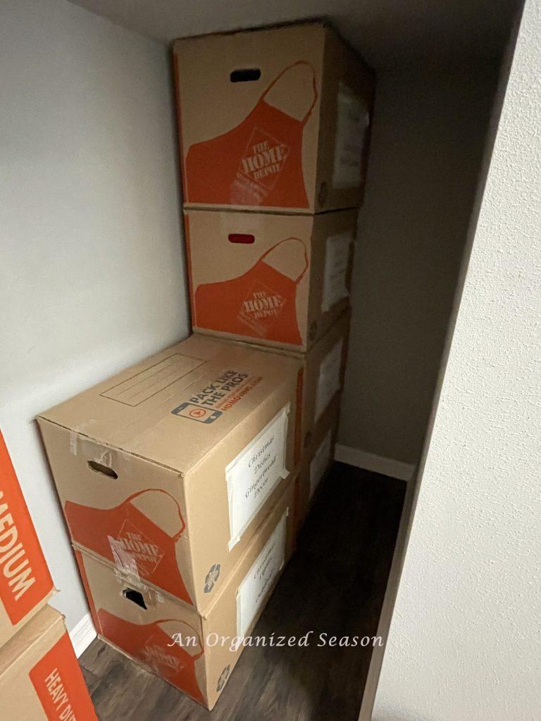Home Depot moving boxes stored under a staircase, an example of tips to organize and store your Christmas decor.