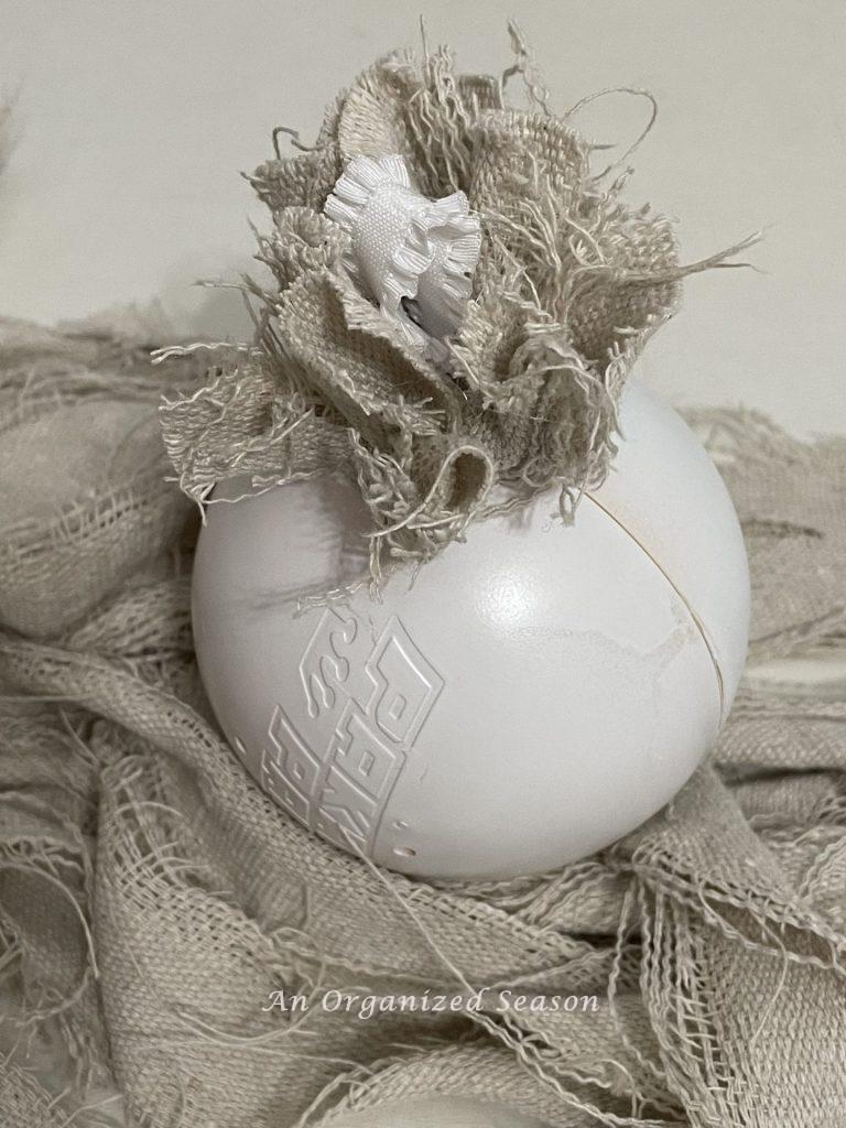 A white ball with drop cloth pieces glued onto it, to make a vintage Christmas ornament. 