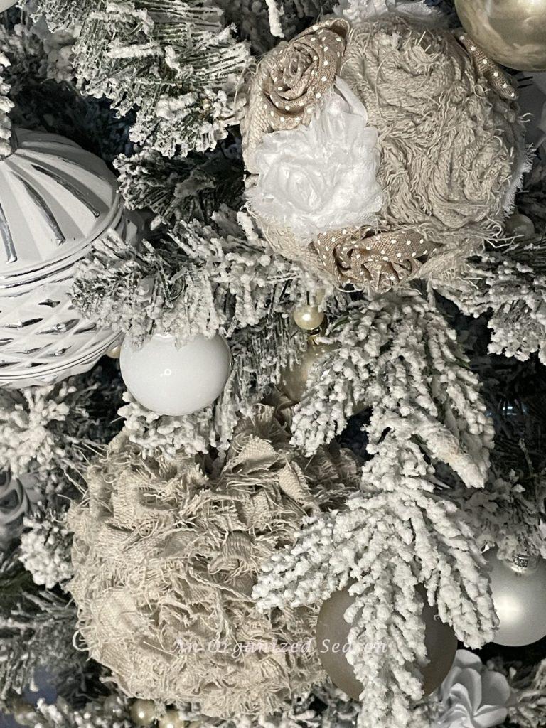 Two vintage drop cloth Christmas ornaments hanging on a flocked tree. 