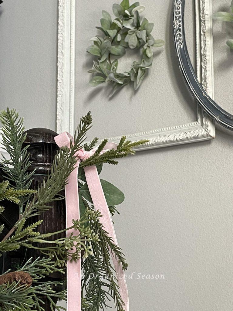 A bow made out of pink velvet ribbon and hanging on a garland  is a good way to decorate for Christmas on a budget.