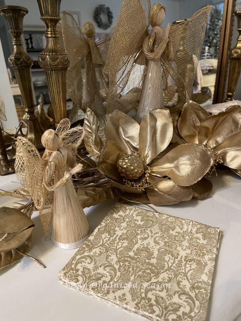 Decorative napkins, next to a gold magnolia spray, to be used to make Christmas ornaments. 