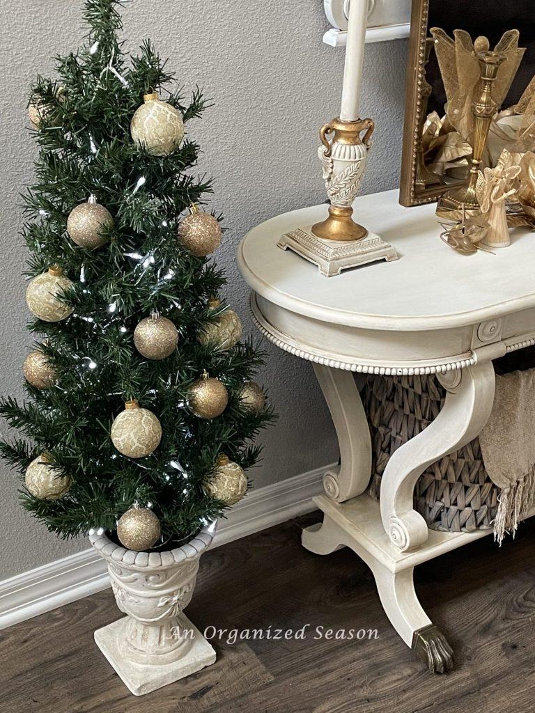 A small Christmas tree covered with gold and cream ornaments. 