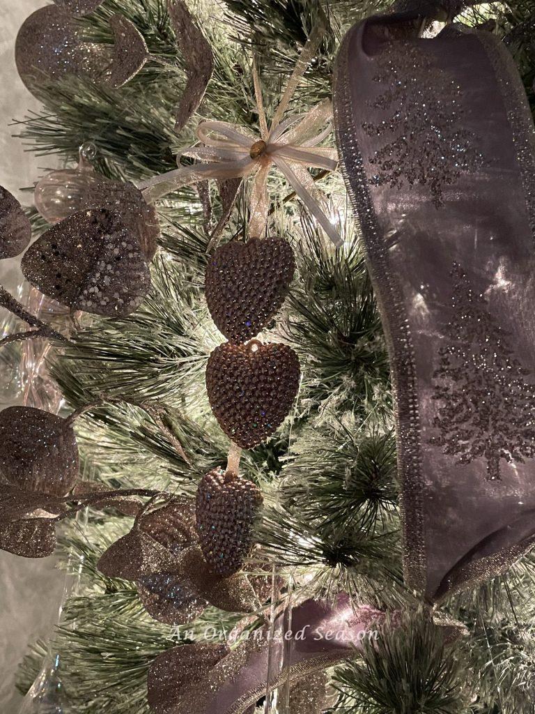 Pink sparkly hearts and ribbon embellished with gold glitter trees decorate a tree at nighttime.