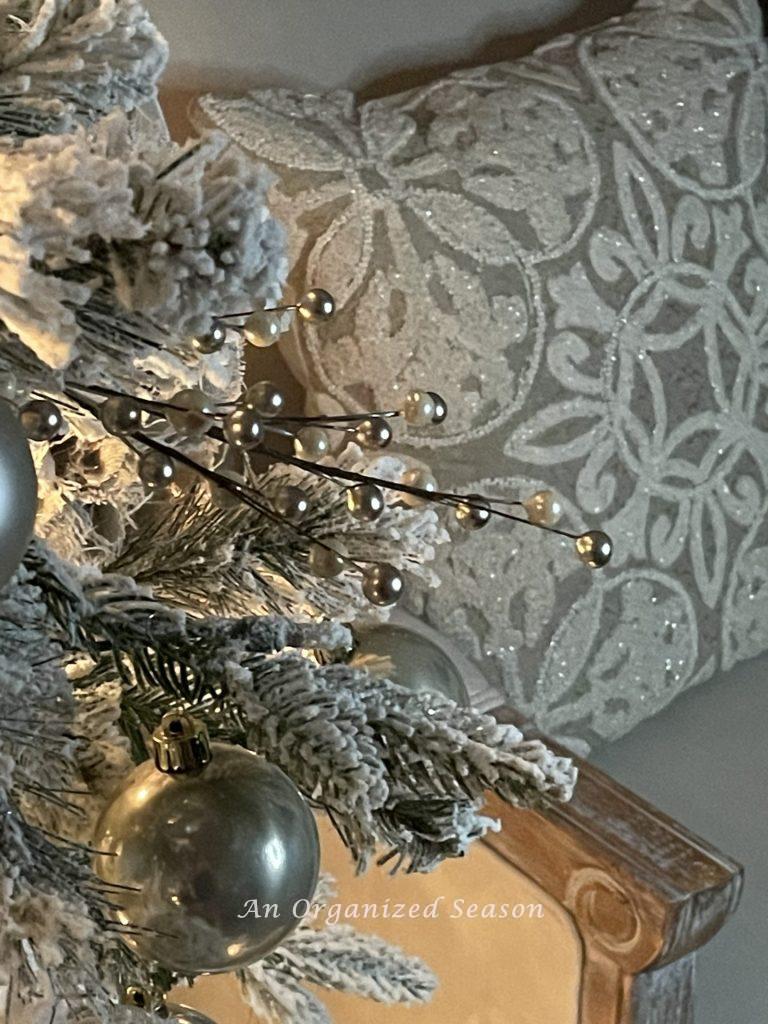 An embroidered pillow sparkles in the light of a Christmas tree during a nighttime home tour. 