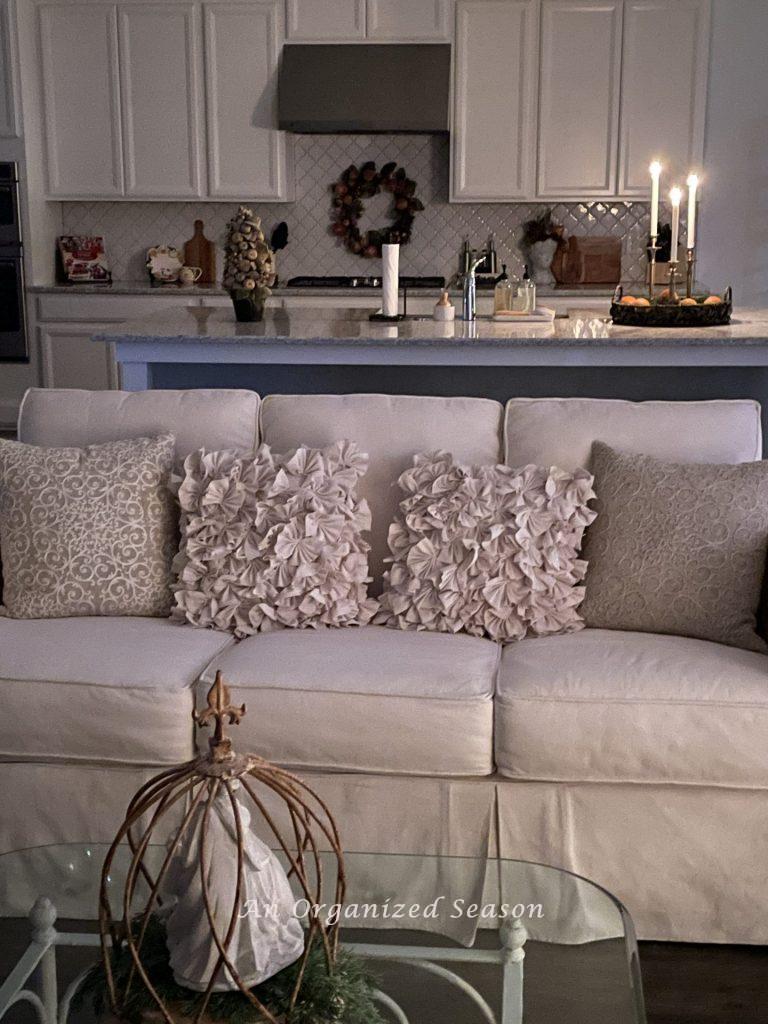 A white kitchen decorated for Christmas with three lit candles on the counter. 