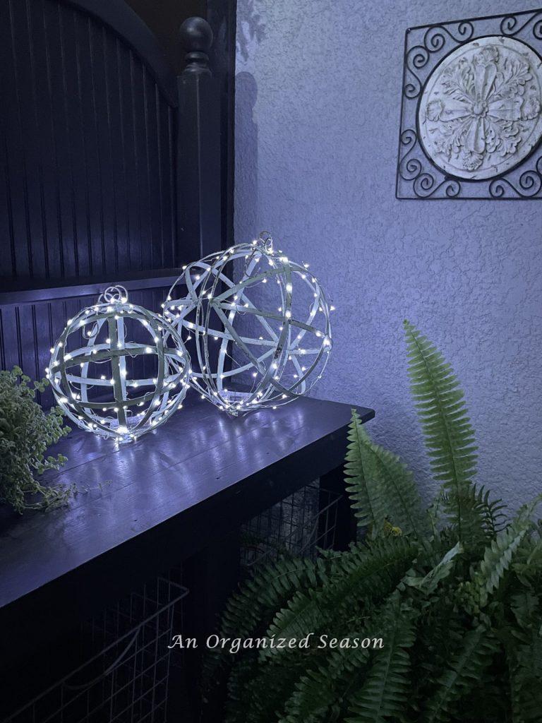 Two metal orbs wrapped with fairy lights, sitting on a potting bench. 