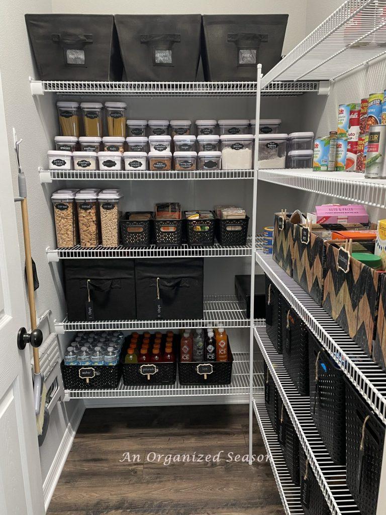 A pantry organized with black bins and OXO storage containers. 